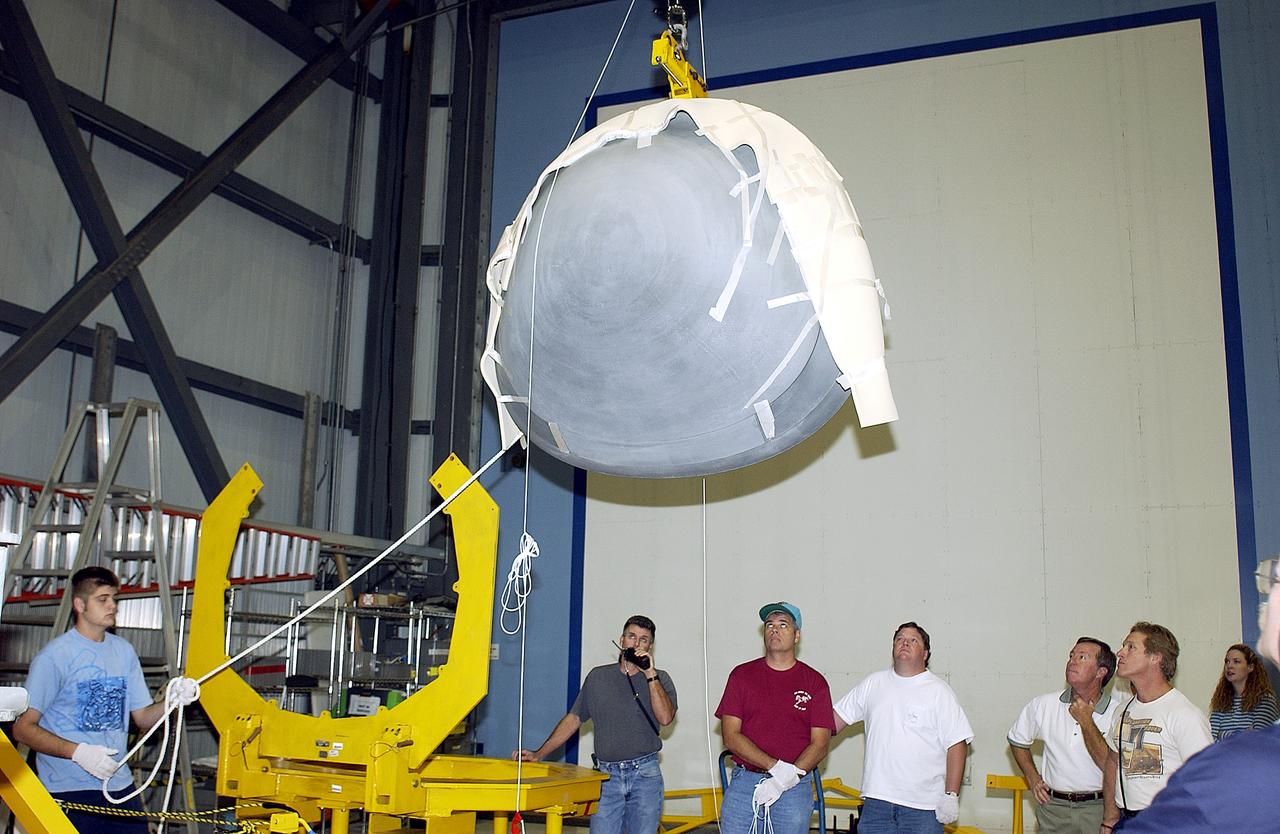 KENNEDY SPACE CENTER, FLA. - In the Orbiter Processing Facility, workers watch as the nose cap of the orbiter Atlantis is moved toward the stand at left.  The cap was removed from the orbiter for routine inspection. The nose cap is made of reinforced carbon-carbon (RCC), which has an operating range of minus 250° F to about 3,000° F.