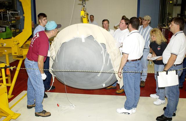 NASA image: KENNEDY SPACE CENTER, FLA. - In the Orbiter Processing Facility, workers watch as the nose cap of the orbiter Atlantis is lowered toward the floor.   The cap was removed from the orbiter for routine inspection. The nose cap is made of reinforced carbon-carbon (RCC), which has an operating range of minus 250° F to about 3,000° F.