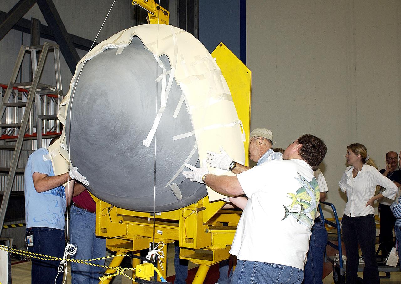 KENNEDY SPACE CENTER, FLA. -  In the Orbiter Processing Facility, workers help guide the nose cap of the orbiter Atlantis toward a stand.  The cap was removed from the orbiter for routine inspection. The nose cap is made of reinforced carbon-carbon (RCC), which has an operating range of minus 250° F to about 3,000° F.