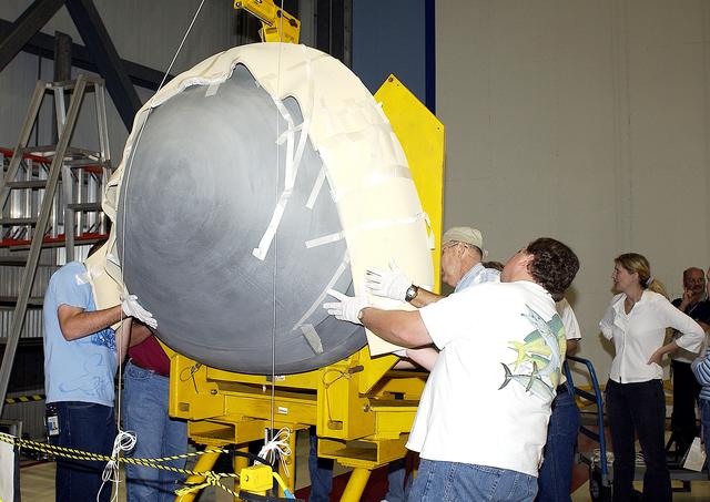 NASA image: KENNEDY SPACE CENTER, FLA. -  In the Orbiter Processing Facility, workers help guide the nose cap of the orbiter Atlantis toward a stand.  The cap was removed from the orbiter for routine inspection. The nose cap is made of reinforced carbon-carbon (RCC), which has an operating range of minus 250° F to about 3,000° F.