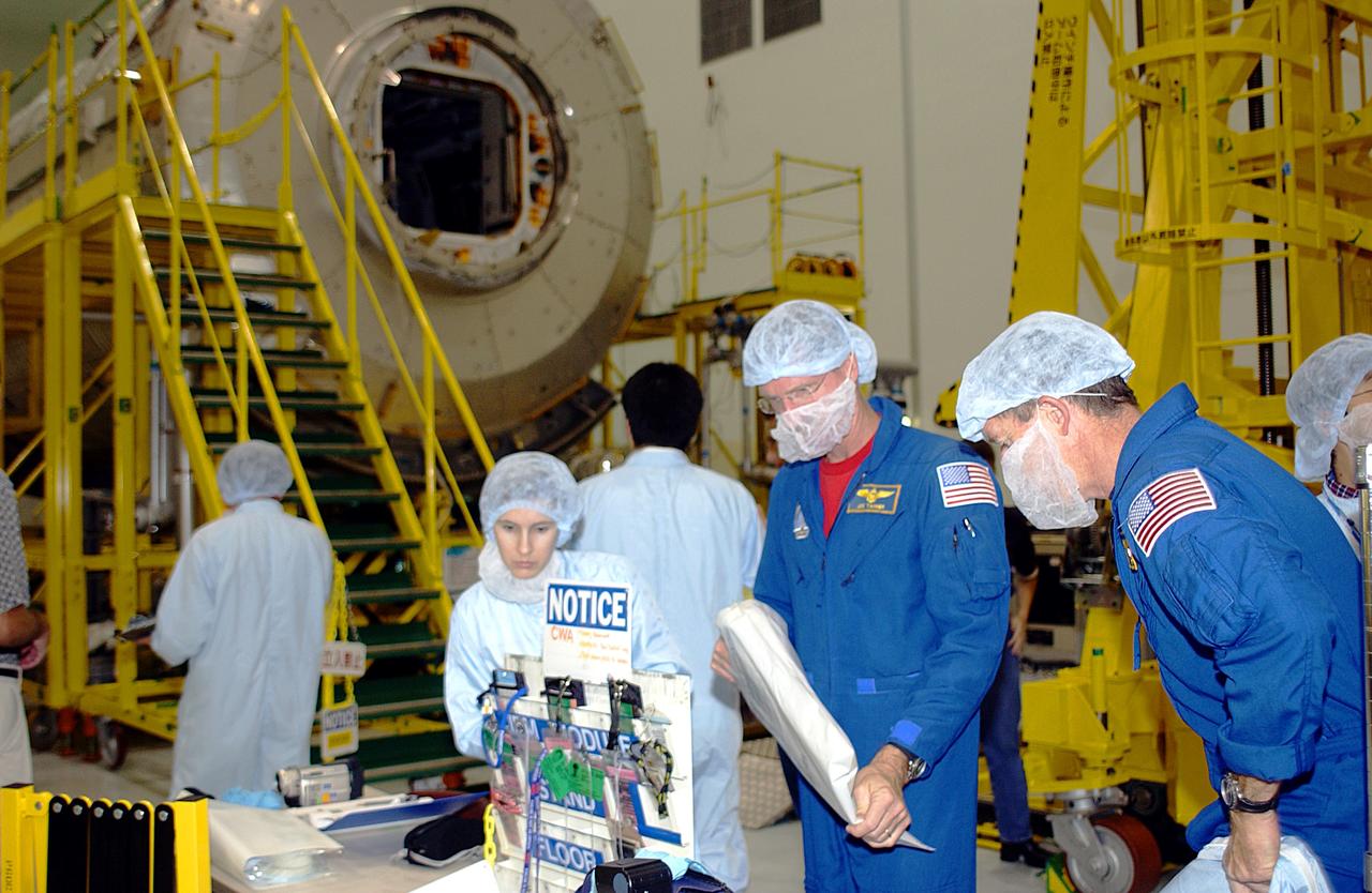 KENNEDY SPACE CENTER, FLA. - In the Space Station Processing Facility, STS-115 Mission Specialist Joseph Tanner (left) and STS-117 Mission Specialist James Reilly (right) are donning protective clothing to interface with the Japanese Experiment Module (JEM), in the background.  Equipment familiarization is a routine part of astronaut training and launch preparations.