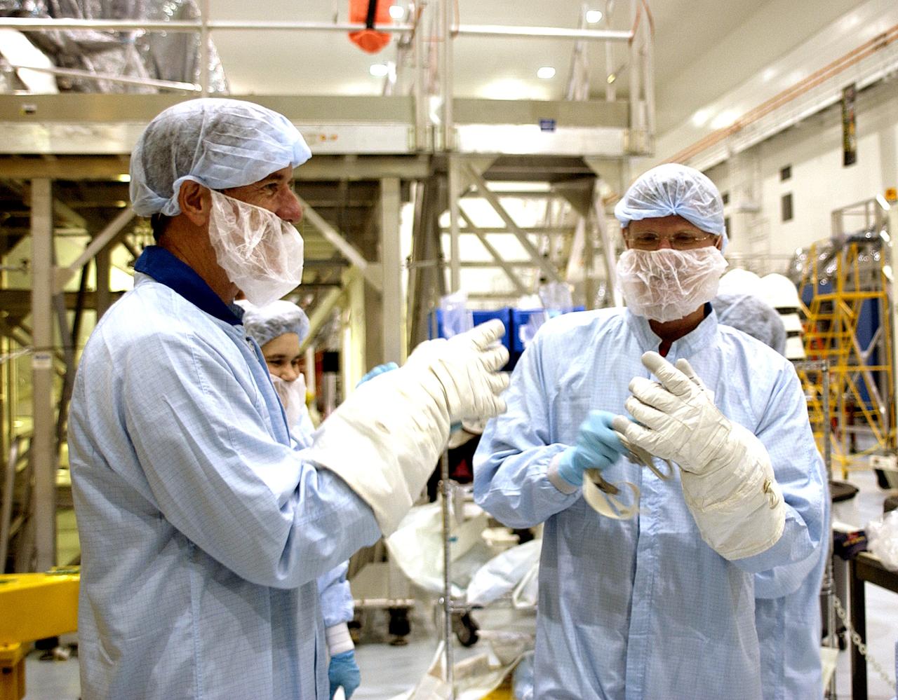 KENNEDY SPACE CENTER, FLA. - STS-117 Mission Specialist James Reilly (left) and STS-115 Mission Specialist Joseph Tanner (right) put on protective gloves before their checkout of the Japanese Experiment Module (JEM) in the Space Station Processing Facility. Reilly and Tanner are at KSC for equipment familiarization, a routine part of astronaut training and launch preparations.