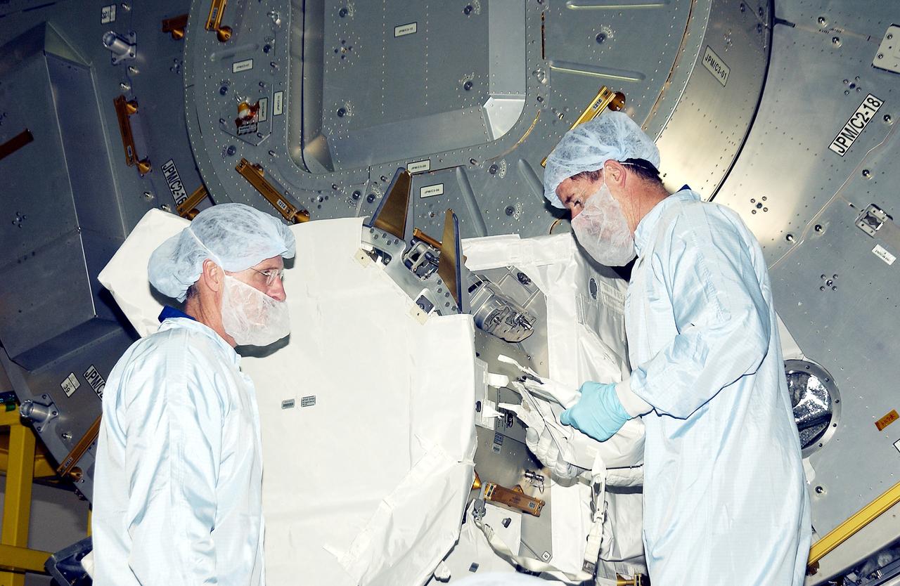 KENNEDY SPACE CENTER, FLA. -  In the Space Station Processing Facility, STS-117 Mission Specialist James Reilly (left) and STS-115 Mission Specialist Joseph Tanner (right) look over components in the Japanese Experiment Module (JEM).  Equipment familiarization is a routine part of astronaut training and launch preparations.