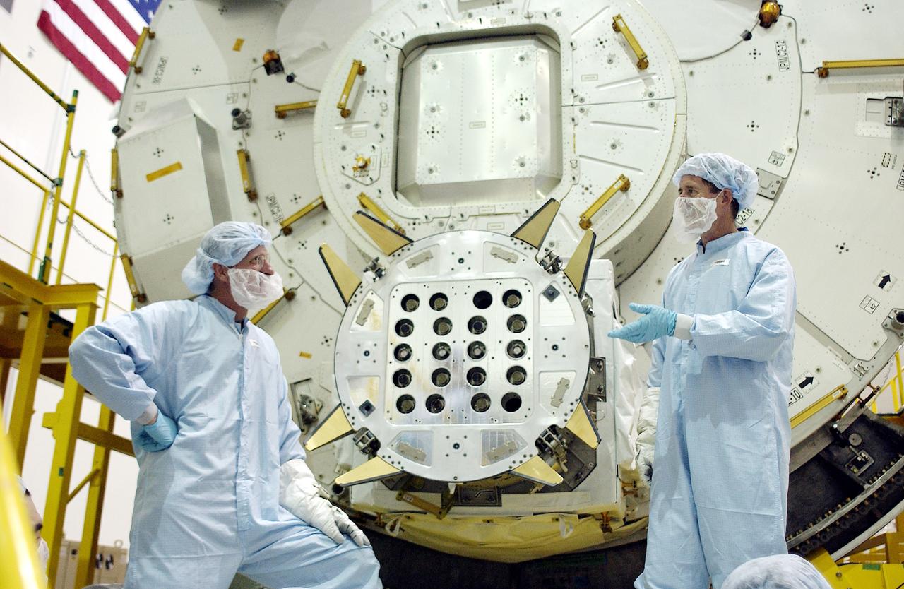 KENNEDY SPACE CENTER, FLA. - In the Space Station Processing Facility, STS-115 Mission Specialist Joseph Tanner (left) and STS-117 Mission Specialist James Reilly (right) talk after removing a cover from the Exposed Facility Berthing Mechanism (EFBM) on the Japanese Experiment Module (JEM) behind them. Equipment familiarization is a routine part of astronaut training and launch preparations.