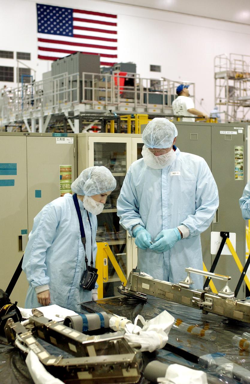 KENNEDY SPACE CENTER, FLA. - In the Space Station Processing Facility, STS-115 Mission Specialist Joseph Tanner (right) checks out a camera and cables for the Japanese Experiment Module (JEM). Known as Kibo, the JEM consists of six components: two research facilities - the Pressurized Module and the Exposed Facility; a Logistics Module attached to each of them; a Remote Manipulator System; and an Inter-Orbit Communication System unit. Kibo also has a scientific airlock through which experiments are transferred and exposed to the external environment of space. The various components of JEM will be assembled in space over the course of three Space Shuttle missions. Equipment familiarization is a routine part of astronaut training and launch preparations.
