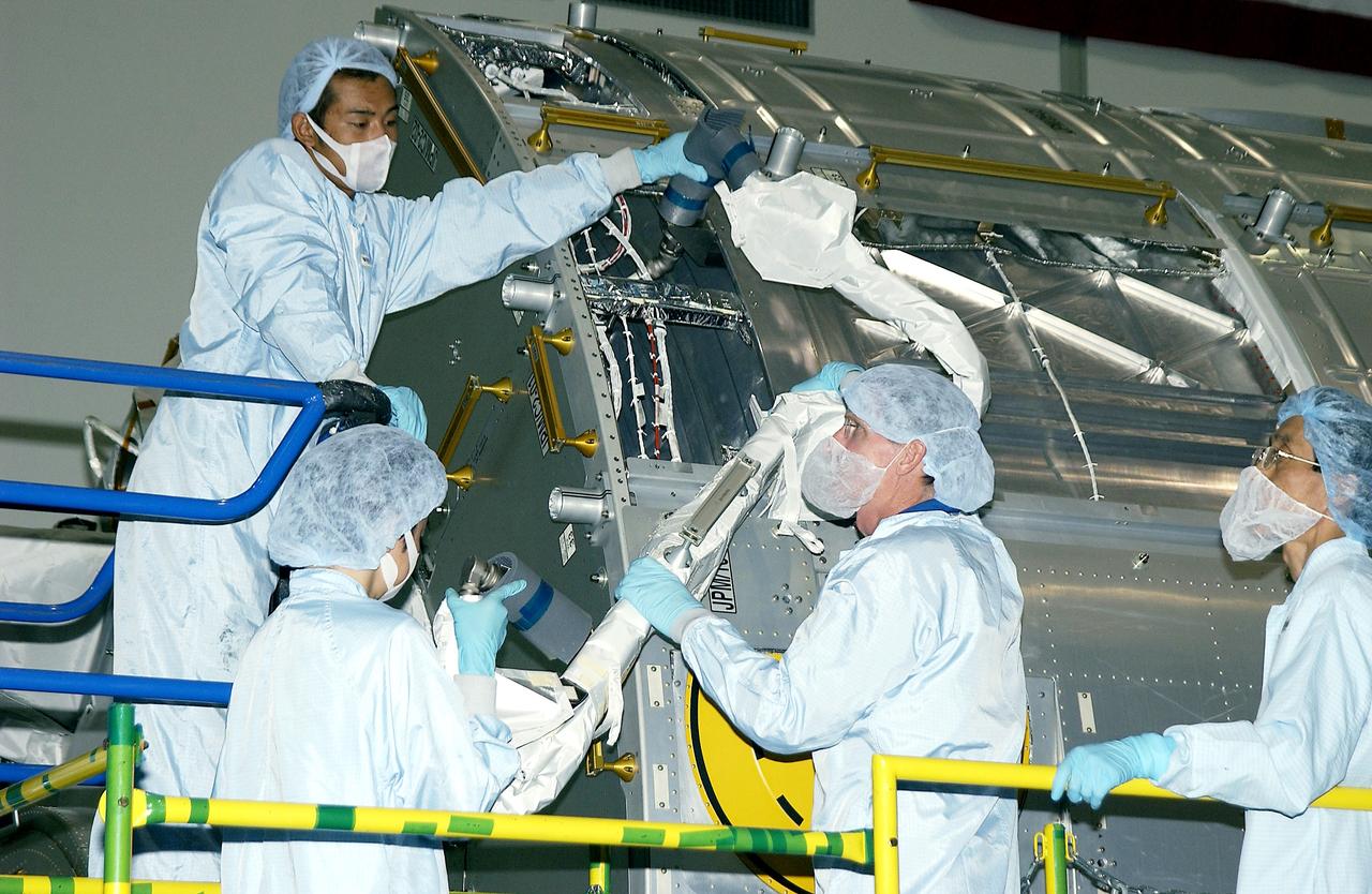 KENNEDY SPACE CENTER, FLA. - In the Space Station Processing Facility, STS-115 Mission Specialist Joseph Tanner (center, foreground) works with technicians to learn more about the Japanese Experiment Module (JEM), known as Kibo. The JEM consists of six components: two research facilities - the Pressurized Module and the Exposed Facility; a Logistics Module attached to each of them; a Remote Manipulator System; and an Inter-Orbit Communication System unit. Kibo also has a scientific airlock through which experiments are transferred and exposed to the external environment of space. The various components of JEM will be assembled in space over the course of three Space Shuttle missions. Equipment familiarization is a routine part of astronaut training and launch preparations.