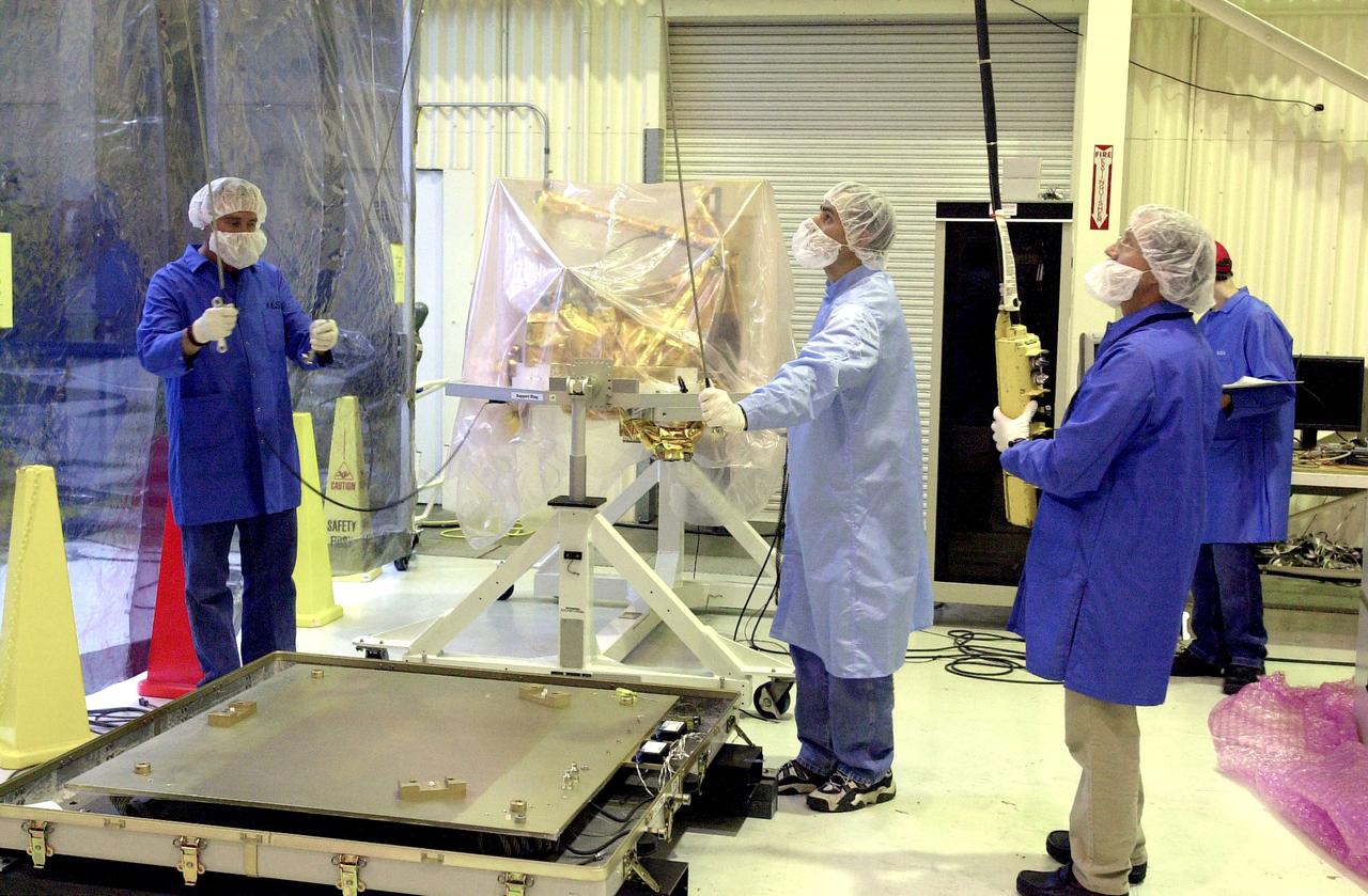 VANDENBERG AIR FORCE BASE, CALIF.  -  Outside the clean room at Vandenberg Air Force Base, Calif., the SciSat-1 spacecraft (background) has been removed from the shipping container mounting base (lower left) and placed on the handling fixture. Sci-Sat, which will undergo instrument checkout and spacecraft functional testing, weighs approximately 330 pounds and after launch will be placed in a 400-mile-high polar orbit to investigate processes that control the distribution of ozone in the upper atmosphere. The data from the satellite will provide Canadian and international scientists with improved measurements relating to global ozone processes and help policymakers assess existing environmental policy and develop protective measures for improving the health of our atmosphere, preventing further ozone depletion. The mission is designed to last two years.