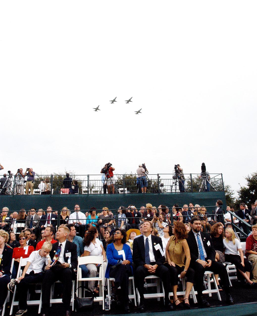 KENNEDY SPACE CENTER, FLA. -- Family members of the STS-107 astronauts and other dignitaries watch NASA T-38 jets fly over the Space Mirror Memorial at the Kennedy Space Center Visitor Complex in a Missing Man Formation. During this dedication ceremony, the names of the STS-107 astronauts who lost their lives during the Columbia accident -- Rick Husband, Willie McCool, Laurel Clark, Michael Anderson, David Brown, Kalpana Chawla, and Ilan Ramon -- join the names of 17 other space heroes who gave their lives for the U.S. space program.