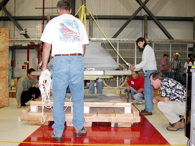 NASA image: KENNEDY SPACE CENTER, FLA. -  In the Orbiter Processing Facility, the nose cap from Atlantis is lowered toward a shipping pallet.  The reinforced carbon-carbon (RCC) nose cap is being sent to the original manufacturing company, Vought in Ft. Worth, Texas, a subsidiary of Lockheed Martin, to undergo non-destructive testing such as CAT scan and thermography.