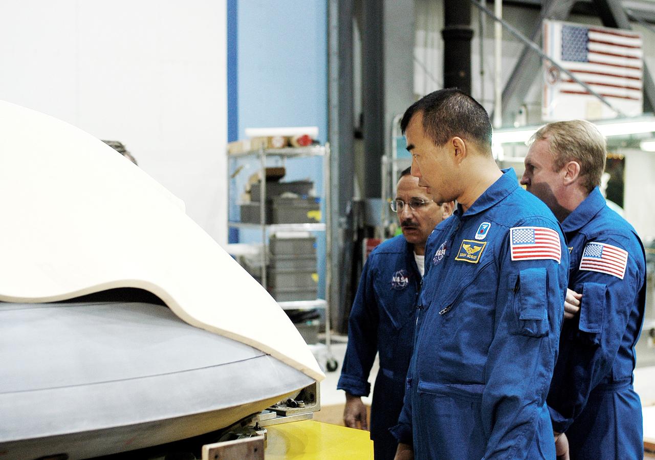 KENNEDY SPACE CENTER, FLA. -  In the Orbiter Processing Facility, STS-114 crew members look at the nose cap recently removed from Atlantis.  From left are Mission Specialists Charles Camarda, Soichi Noguchi, and Andy Thomas.  Camarda and Thomas are new additions to the crew.  Noguchi is with the Japan Aerospace Exploration Agency, JAXA. The STS-114 crew is at KSC to take part in crew equipment and orbiter familiarization.