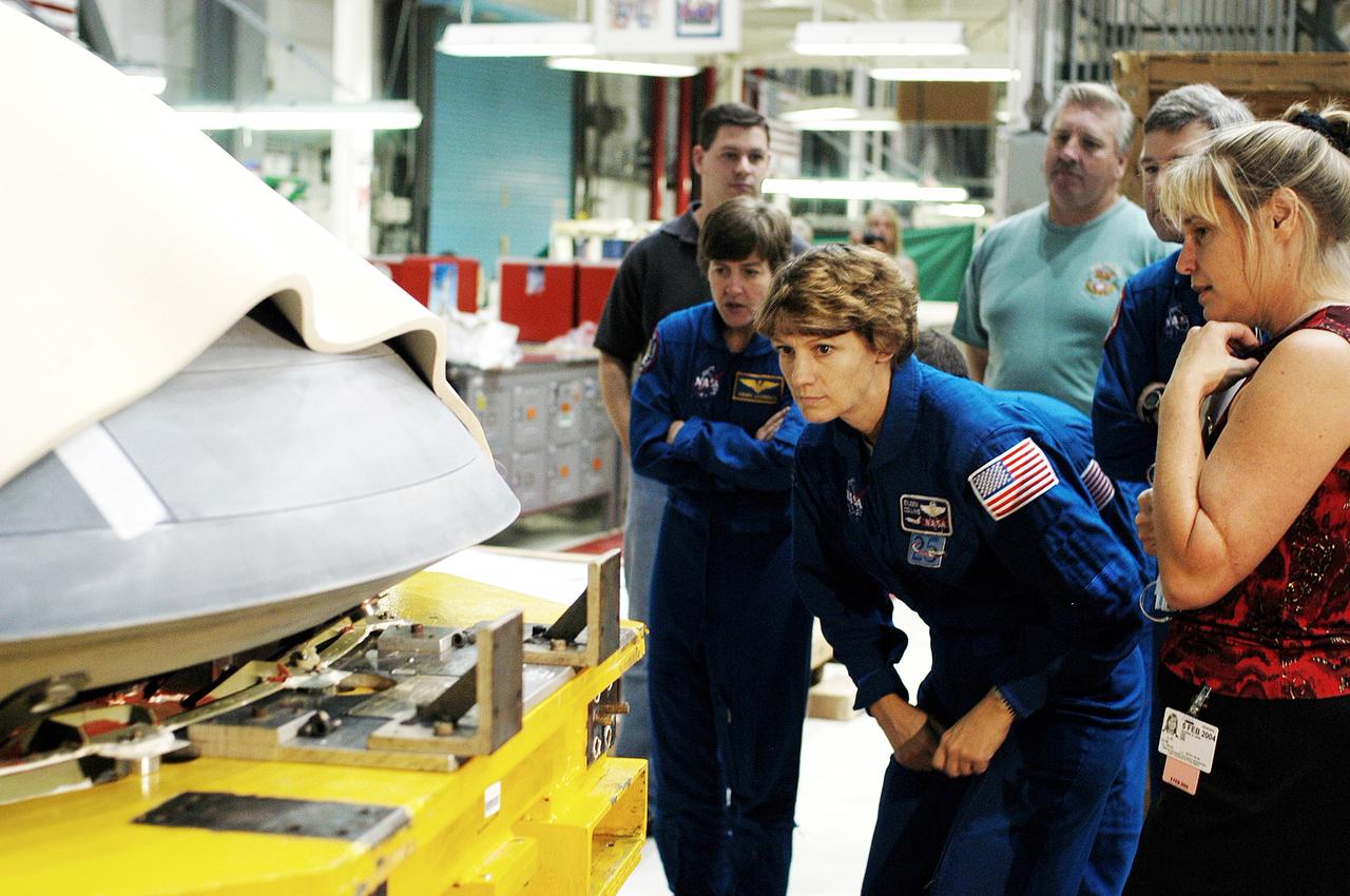 KENNEDY SPACE CENTER, FLA. -  In the Orbiter Processing Facility, STS-114 crew members look at the nose cap recently removed from Atlantis.  From left are Mission Specialist Wendy Lawrence, Commander Eileen Collins and Pilot James Kelly (behind Collins).  Lawrence is a new addition to the mission crew.  The STS-114 crew is at KSC to take part in crew equipment and orbiter familiarization.
