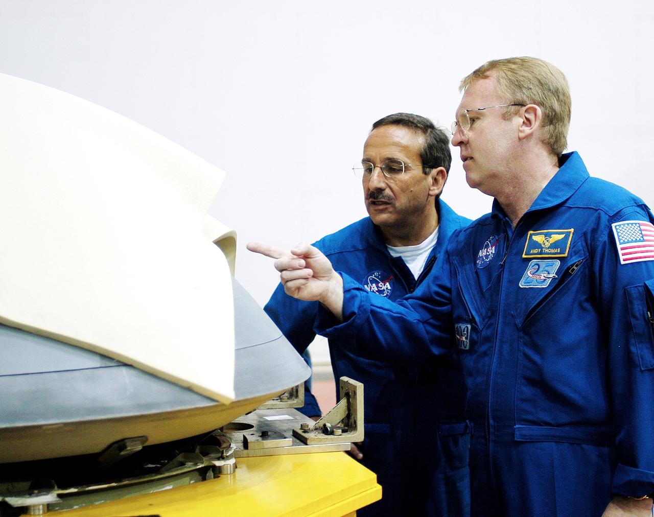 KENNEDY SPACE CENTER, FLA. -  In the Orbiter Processing Facility, STS-114 Mission Specialists Charles Camarda and Andy Thomas, who were recently added to the crew, look at the nose cap recently removed from Atlantis.  The STS-114 crew is at KSC to take part in crew equipment and orbiter familiarization.
