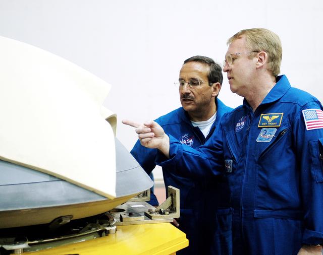 NASA image: KENNEDY SPACE CENTER, FLA. -  In the Orbiter Processing Facility, STS-114 Mission Specialists Charles Camarda and Andy Thomas, who were recently added to the crew, look at the nose cap recently removed from Atlantis.  The STS-114 crew is at KSC to take part in crew equipment and orbiter familiarization.
