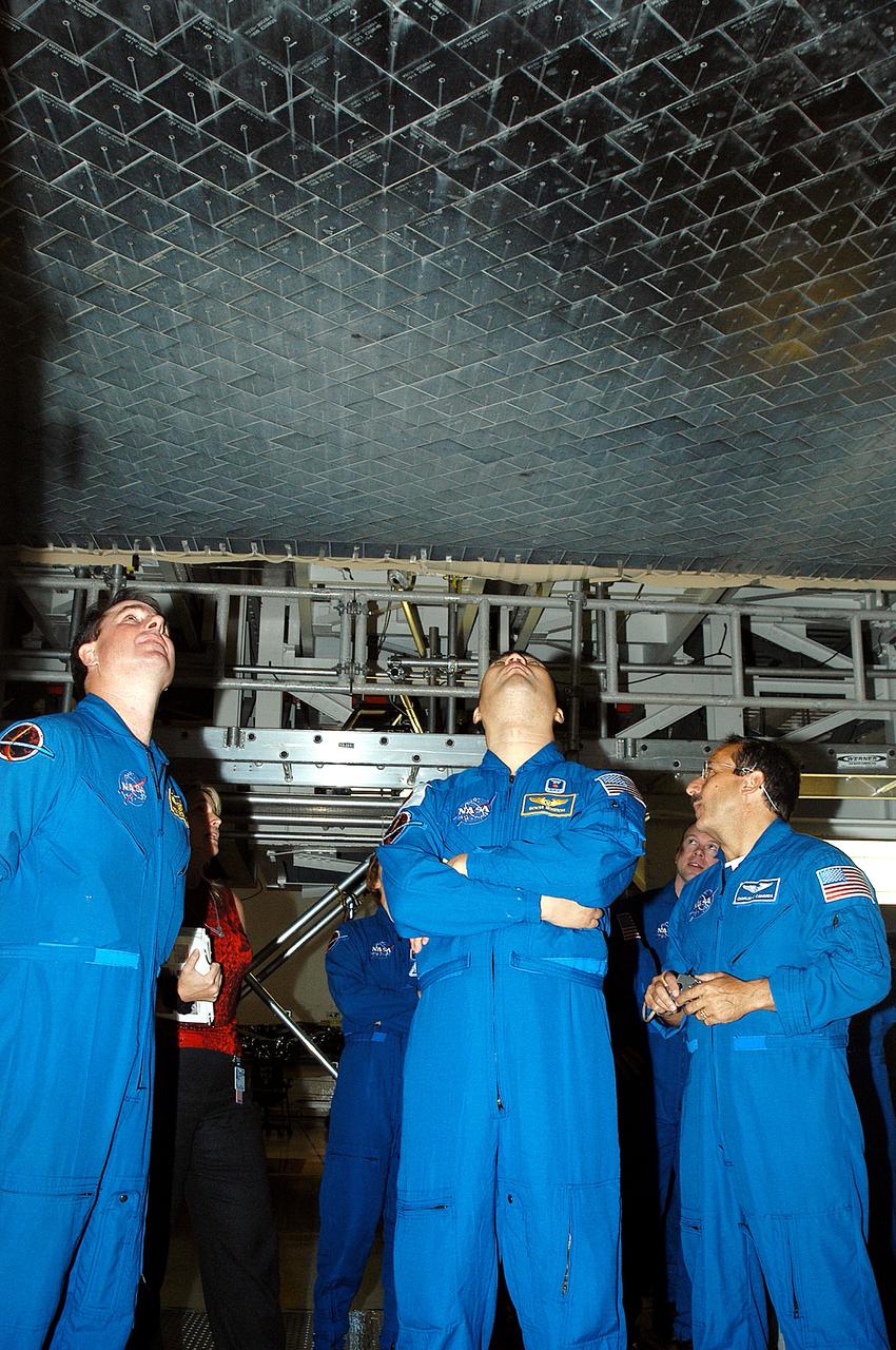 KENNEDY SPACE CENTER, FLA. -  In the Orbiter Processing Facility, STS-114 crew members look at the tiles underneath Atlantis.  From left are Mission Specialists Stephen Robinson, Soichi Noguchi and Charles Camarada, who is a new addition to the crew.  Noguchi is with the Japan Aerospace Exploration Agency, JAXA.  The STS-114 crew is at KSC to take part in crew equipment and orbiter familiarization.
