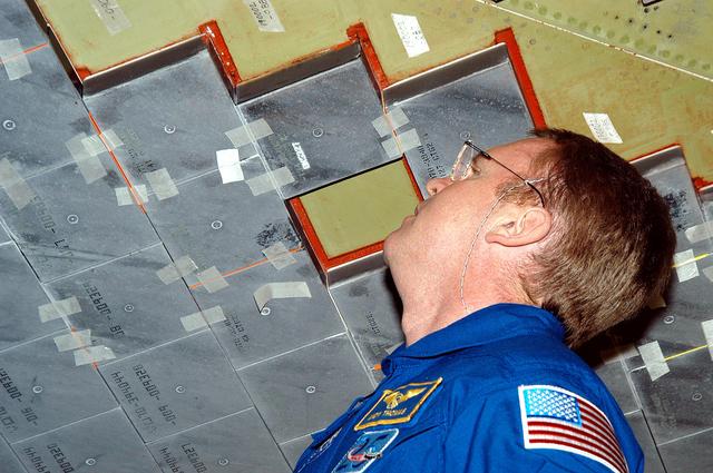 NASA image: KENNEDY SPACE CENTER, FLA. -  In the Orbiter Processing Facility, STS-114 Mission Specialist Andy Thomas takes a close look at the some of the tiles underneath Atlantis.  Thomas is a new addition to the mission crew.  The STS-114 crew is at KSC to take part in crew equipment and orbiter familiarization.