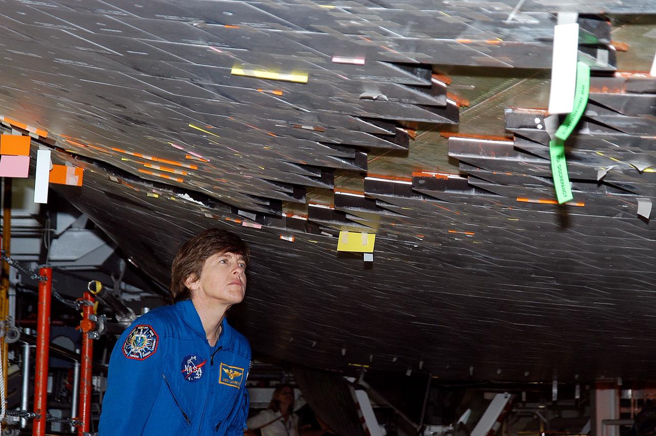 KENNEDY SPACE CENTER, FLA. -  In the Orbiter Processing Facility, STS-114 Mission Specialist Wendy Lawrence takes a close look at the some of the tiles underneath Atlantis.  Lawrence is a new addition to the mission crew.  The STS-114 crew is at KSC to take part in crew equipment and orbiter familiarization.