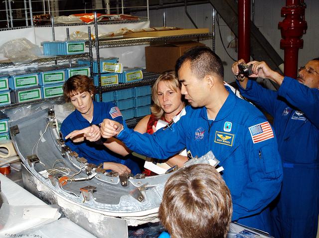 NASA image: KENNEDY SPACE CENTER, FLA. - Members of the STS-114 crew look over flight  equipment in the Orbiter Processing Facility.  From left are Mission Commander Eileen Collins; Glenda Laws, EVA Task Leader, with United Space Alliance at Johnson Space Center; and Mission Specialists Soichi Noguchi and Charles Camarda.  In the foreground is Mission Specialist Wendy Lawrence.  Noguchi is with the Japan Aerospace Exploration Agency, JAXA. Not seen are Pilot James Kelly and Mission Specialists Andy Thomas and Stephen Robinson.  The STS-114 crew is at KSC to take part in crew equipment and orbiter familiarization.