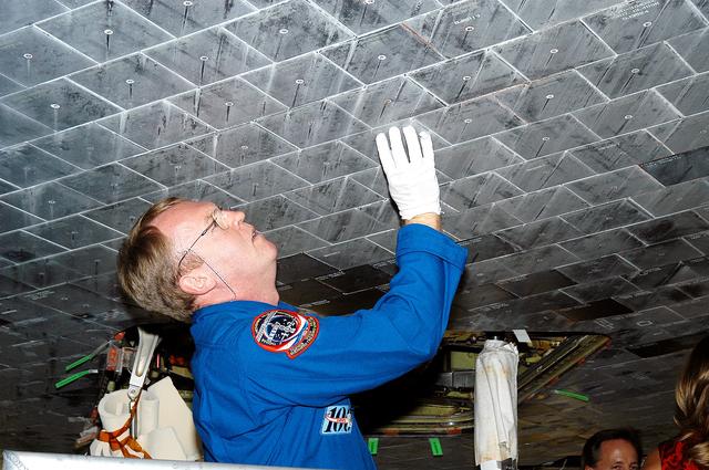 NASA image: KENNEDY SPACE CENTER, FLA. -  In the Orbiter Processing Facility, STS-114 Mission Specialist Andy Thomas takes a close look at the some of the tiles underneath Atlantis.  Thomas is a new addition to the mission crew.  The STS-114 crew is at KSC to take part in crew equipment and orbiter familiarization.