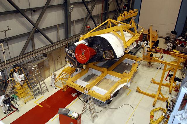 NASA image: KENNEDY SPACE CENTER, FLA. - In the Orbiter Processing Facility, one of two orbital maneuvering system (OMS) pods is being moved for installation on Atlantis.  The OMS pods are attached to the upper aft fuselage left and right sides. Fabricated primarily of graphite epoxy composite and aluminum, each pod is 21.8 feet long and 11.37 feet wide at its aft end and 8.41 feet wide at its forward end, with a surface area of approximately 435 square feet. Each pod houses the Reaction Control System propulsion components used for inflight maneuvering and is attached to the aft fuselage with 11 bolts.