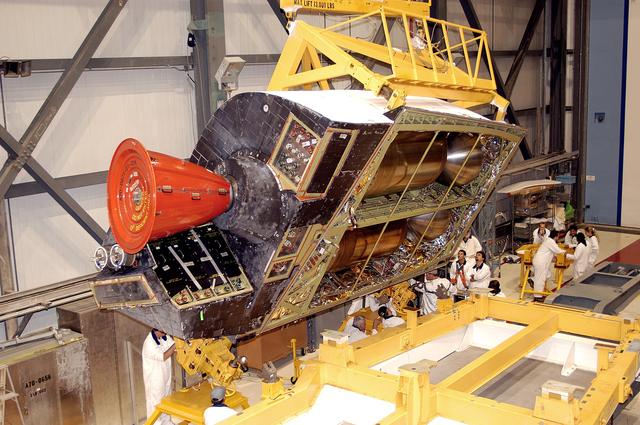 NASA image: KENNEDY SPACE CENTER, FLA. -  In the Orbiter Processing Facility, one of two orbital maneuvering system (OMS) pods is lifted off its stand to move it toward Atlantis for installation. The OMS pods are attached to the upper aft fuselage left and right sides. Fabricated primarily of graphite epoxy composite and aluminum, each pod is 21.8 feet long and 11.37 feet wide at its aft end and 8.41 feet wide at its forward end, with a surface area of approximately 435 square feet. Each pod houses the Reaction Control System propulsion components used for inflight maneuvering and is attached to the aft fuselage with 11 bolts.