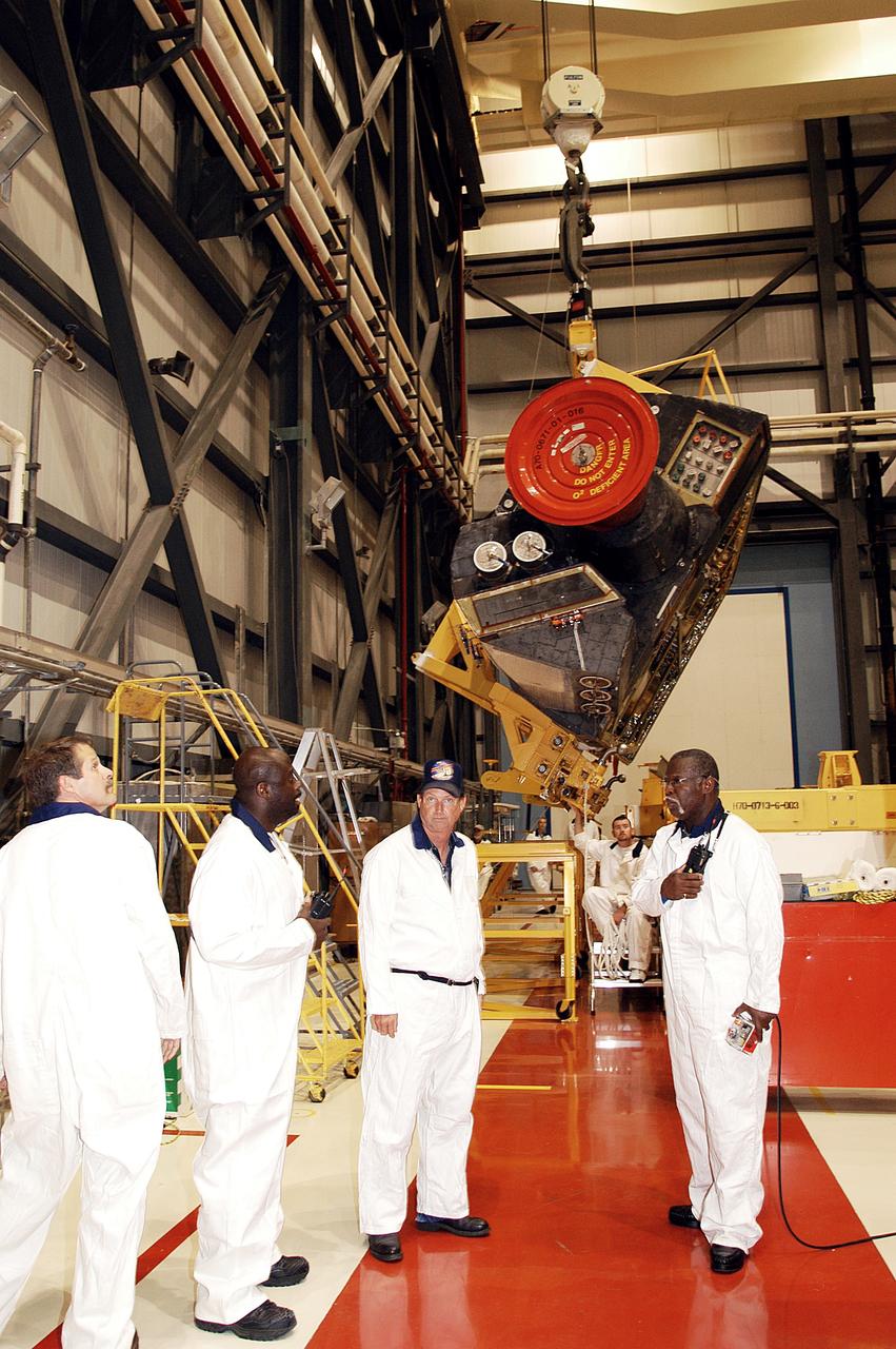 KENNEDY SPACE CENTER, FLA. - In the Orbiter Processing Facility, workers discuss the next step in moving the orbital maneuvering system (OMS) pod behind them.  The OMS pod will be installed on Atlantis.  Two OMS pods are attached to the upper aft fuselage left and right sides. Fabricated primarily of graphite epoxy composite and aluminum, each pod is 21.8 feet long and 11.37 feet wide at its aft end and 8.41 feet wide at its forward end, with a surface area of approximately 435 square feet. Each pod houses the Reaction Control System propulsion components used for inflight maneuvering and is attached to the aft fuselage with 11 bolts.