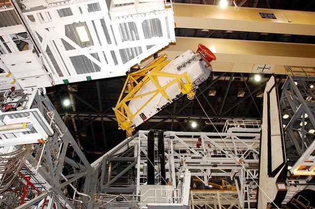 NASA image: KENNEDY SPACE CENTER, FLA. -  In the Orbiter Processing Facility, an orbital maneuvering system (OMS) pod is suspended in air as it is moved toward Atlantis for installation.  Two OMS pods are attached to the upper aft fuselage left and right sides. Fabricated primarily of graphite epoxy composite and aluminum, each pod is 21.8 feet long and 11.37 feet wide at its aft end and 8.41 feet wide at its forward end, with a surface area of approximately 435 square feet. Each pod houses the Reaction Control System propulsion components used for inflight maneuvering and is attached to the aft fuselage with 11 bolts.