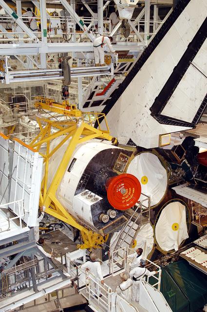 NASA image: KENNEDY SPACE CENTER, FLA. - In the Orbiter Processing Facility, an orbital maneuvering system (OMS) pod is moved into place on Atlantis.  It is one of two OMS pods attached to the upper aft fuselage left and right sides. Fabricated primarily of graphite epoxy composite and aluminum, each pod is 21.8 feet long and 11.37 feet wide at its aft end and 8.41 feet wide at its forward end, with a surface area of approximately 435 square feet. Each pod houses the Reaction Control System propulsion components used for inflight maneuvering and is attached to the aft fuselage with 11 bolts.
