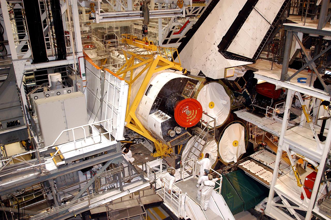 KENNEDY SPACE CENTER, FLA. - In the Orbiter Processing Facility, an orbital maneuvering system (OMS) pod is moved into place on Atlantis.  It is one of two OMS pods attached to the upper aft fuselage left and right sides. Fabricated primarily of graphite epoxy composite and aluminum, each pod is 21.8 feet long and 11.37 feet wide at its aft end and 8.41 feet wide at its forward end, with a surface area of approximately 435 square feet. Each pod houses the Reaction Control System propulsion components used for inflight maneuvering and is attached to the aft fuselage with 11 bolts.