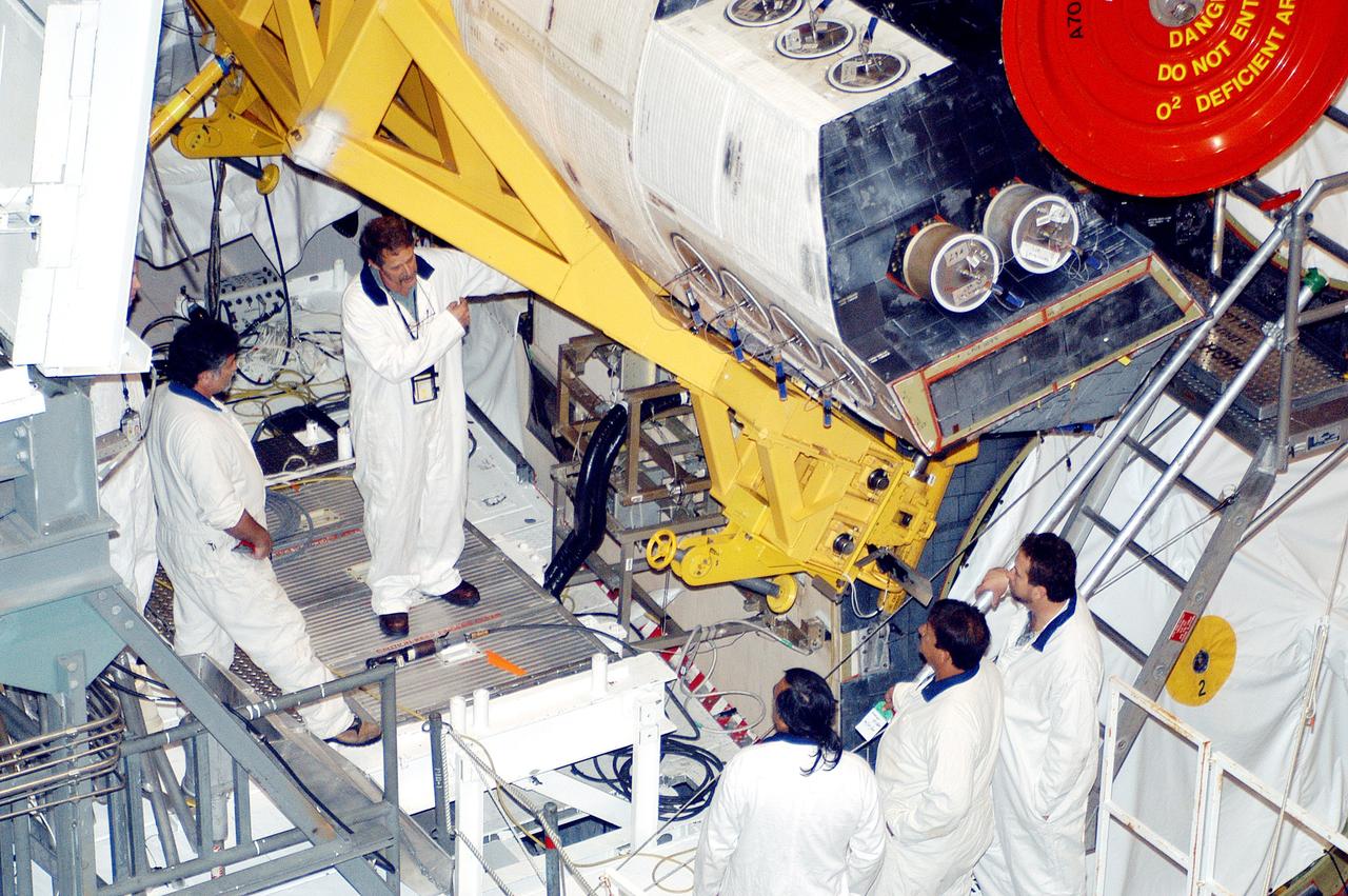 KENNEDY SPACE CENTER, FLA. - In the Orbiter Processing Facility, technicians move an orbital maneuvering system (OMS) pod into the correct position on Atlantis. The OMS pod is one of two that are attached to the upper aft fuselage left and right sides. Fabricated primarily of graphite epoxy composite and aluminum, each pod is 21.8 feet long and 11.37 feet wide at its aft end and 8.41 feet wide at its forward end, with a surface area of approximately 435 square feet. Each pod houses the Reaction Control System propulsion components used for inflight maneuvering and is attached to the aft fuselage with 11 bolts.