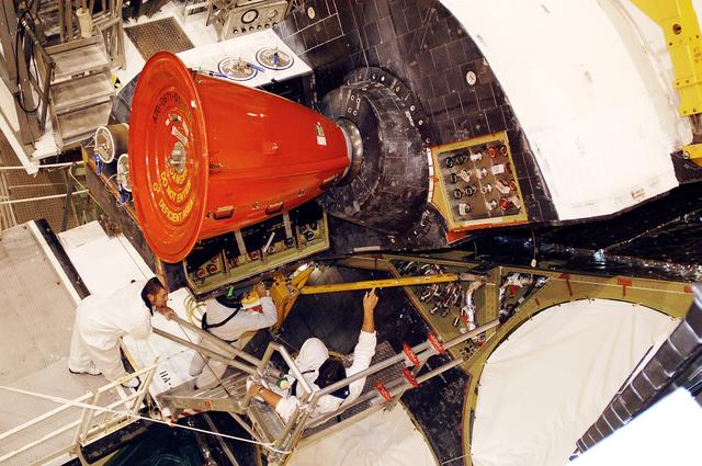 NASA image: KENNEDY SPACE CENTER, FLA. -  In the Orbiter Processing Facility, technicians move an orbital maneuvering system (OMS) pod into the correct position on Atlantis. The OMS pod is one of two that are attached to the upper aft fuselage left and right sides. Fabricated primarily of graphite epoxy composite and aluminum, each pod is 21.8 feet long and 11.37 feet wide at its aft end and 8.41 feet wide at its forward end, with a surface area of approximately 435 square feet. Each pod houses the Reaction Control System propulsion components used for inflight maneuvering and is attached to the aft fuselage with 11 bolts.
