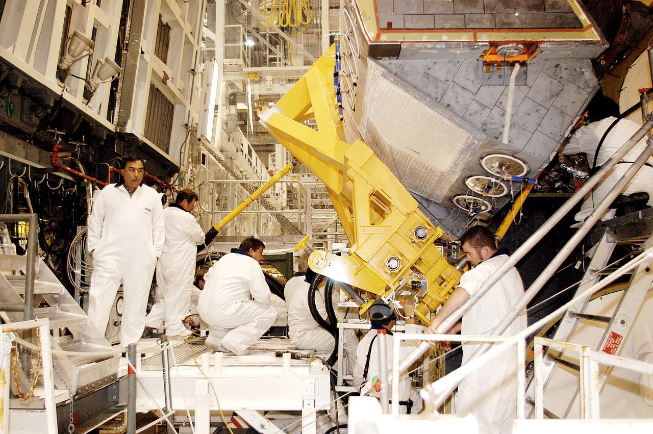 KENNEDY SPACE CENTER, FLA. - In the Orbiter Processing Facility, technicians make final adjustments to the orbital maneuvering system (OMS) pod being installed on Atlantis.   The OMS pod is one of two that are attached to the upper aft fuselage left and right sides. Fabricated primarily of graphite epoxy composite and aluminum, each pod is 21.8 feet long and 11.37 feet wide at its aft end and 8.41 feet wide at its forward end, with a surface area of approximately 435 square feet. Each pod houses the Reaction Control System propulsion components used for inflight maneuvering and is attached to the aft fuselage with 11 bolts.