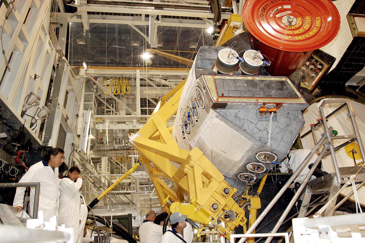 KENNEDY SPACE CENTER, FLA. - In the Orbiter Processing Facility, technicians make final adjustments to the orbital maneuvering system (OMS) pod being installed on Atlantis.   The OMS pod is one of two that are attached to the upper aft fuselage left and right sides. Fabricated primarily of graphite epoxy composite and aluminum, each pod is 21.8 feet long and 11.37 feet wide at its aft end and 8.41 feet wide at its forward end, with a surface area of approximately 435 square feet. Each pod houses the Reaction Control System propulsion components used for inflight maneuvering and is attached to the aft fuselage with 11 bolts.