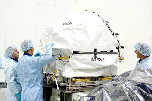 NASA image: KENNEDY SPACE CENTER, FLA. - In the Space Station Processing Facility, members of the STS-114 crew look at a Control Moment Gyroscope.  From left are Mission Specialists Andrew Thomas, Soichi Noguchi and Stephen Robinson.  Noguchi is with the Japan Aerospace Exploration Agency, JAXA.  Thomas is a new addition to the mission crew. The STS-114 crew is at KSC to take part in crew equipment and orbiter familiarization.