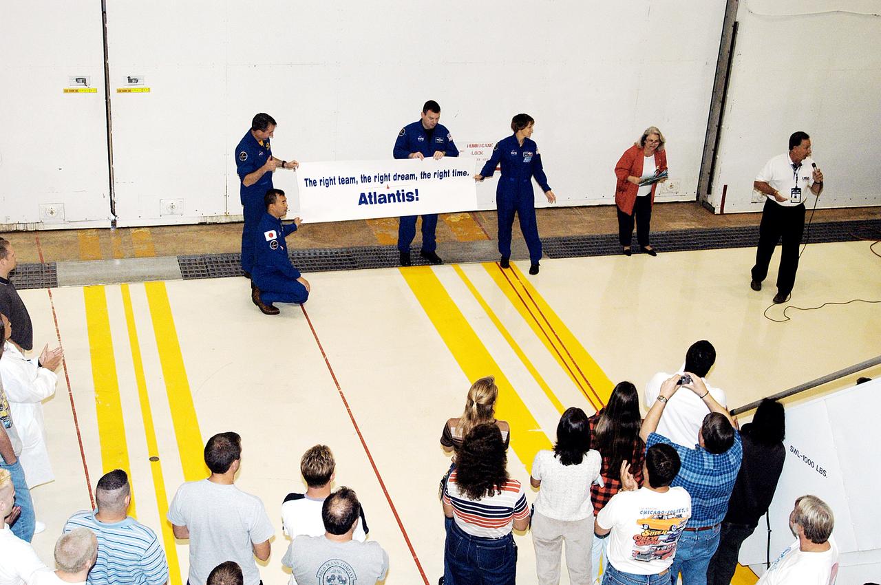 KENNEDY SPACE CENTER, FLA. - Members of the STS-114 crew hold a sign presented to  workers in the Orbiter Processing Facility.  From left are  Mission Specialists Soichi Noguchi (kneeling) and Stephen Robinson, Pilot James Kelly and Mission Commander Eileen Collins. Noguchi is with the Japan Aerospace Exploration Agency, JAXA.  The STS-114 crew is at KSC to take part in crew equipment and orbiter familiarization.