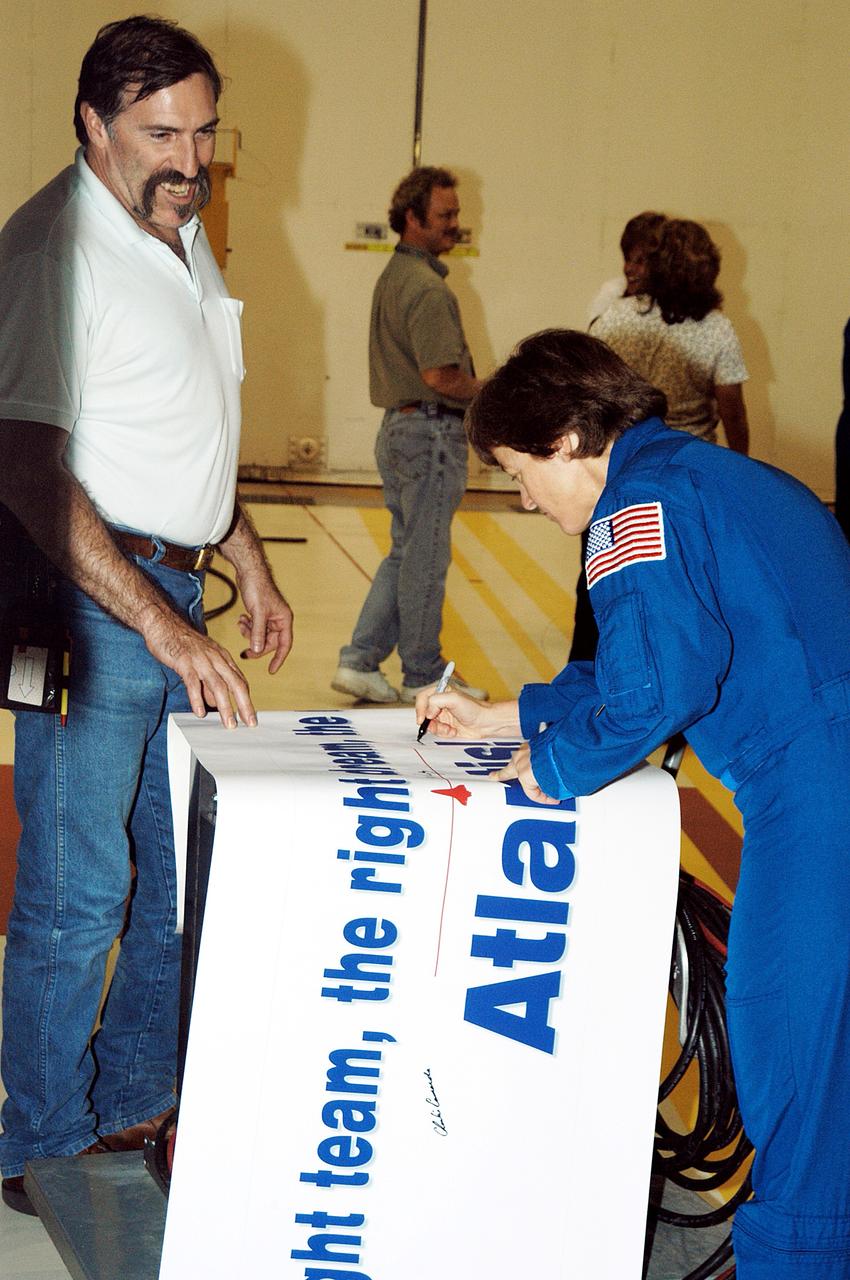 KENNEDY SPACE CENTER, FLA. - STS-114 Mission Specialist Wendy Lawrence autographs the sign presented to  workers in the Orbiter Processing Facility. Lawrence is a new addition to the crew.  The STS-114 crew is at KSC to take part in crew equipment and orbiter familiarization.