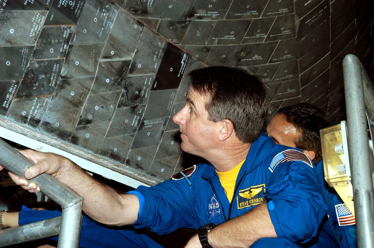 KENNEDY SPACE CENTER, FLA. - In the Orbiter Processing Facility, STS-114 Mission Specialist Stephen Robinson looks closely at the tiles underneath the orbiter Atlantis.  The STS-114 crew is at KSC to take part in crew equipment and orbiter familiarization.