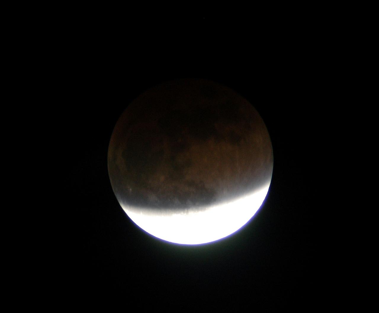 KENNEDY SPACE CENTER, FLA. - In this lunar eclipse viewed from Merritt Island, Fla., the full moon changes color because it is being lighted slightly by sunlight passing through the Earth’s atmosphere.  The earlier reddish color is fading but still somewhat visible on the darker, upper portion.  Eclipses occur when the Sun, Earth and Moon line up. They are rare because the Moon usually passes above or below the imaginary line connecting Earth and the Sun. The Earth casts a shadow that the Moon can pass through - when it does, it is called a lunar eclipse.
