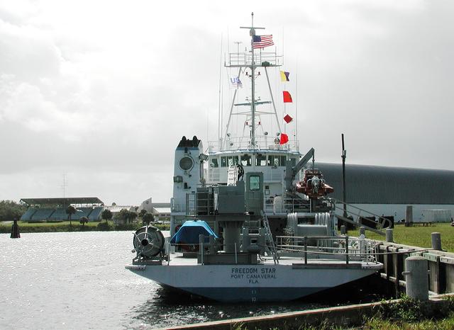 NASA image: KENNEDY SPACE CENTER, FLA. - The Freedom Star is berthed at the Turn Basin near the Vehicle Assembly Building.  The ship has recently returned to KSC after refurbishment at Fort George Island, Fla., including new paint.  Freedom Star is one of the solid rocket booster (SRB) retrieval ships built to recover the SRB casings released over the Atlantic Ocean after launch of a Space Shuttle.  In addition to the SRBs, the ship recovers the drogue and main parachutes that slow the boosters’ speed before splashdown.  Some of the retrieval equipment can be seen on the rear deck.  The ships also tow the external tanks built at the Michoud Space Systems Assembly Facility near New Orleans to Port Canaveral, Fla.  Freedom Star was brought to KSC today for a visit by NATO Parliamentarians.