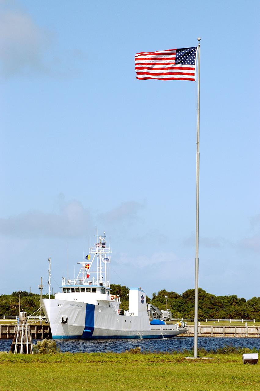 KENNEDY SPACE CENTER, FLA. -  The Freedom Star is berthed at the Turn Basin near the Vehicle Assembly Building and NASA-KSC News Center.  The flag is near the News Center.   The ship has recently returned to KSC after refurbishment at Fort George Island, Fla., including new paint.  Freedom Star is one of the solid rocket booster (SRB) retrieval ships built to recover the SRB casings released over the Atlantic Ocean after launch of a Space Shuttle.  In addition to the SRBs, the ship recovers the drogue and main parachutes that slow the boosters’ speed before splashdown.   The ships also tow the external tanks built at the Michoud Space Systems Assembly Facility near New Orleans to Port Canaveral, Fla.  Freedom Star was brought to KSC today for a visit by NATO Parliamentarians.