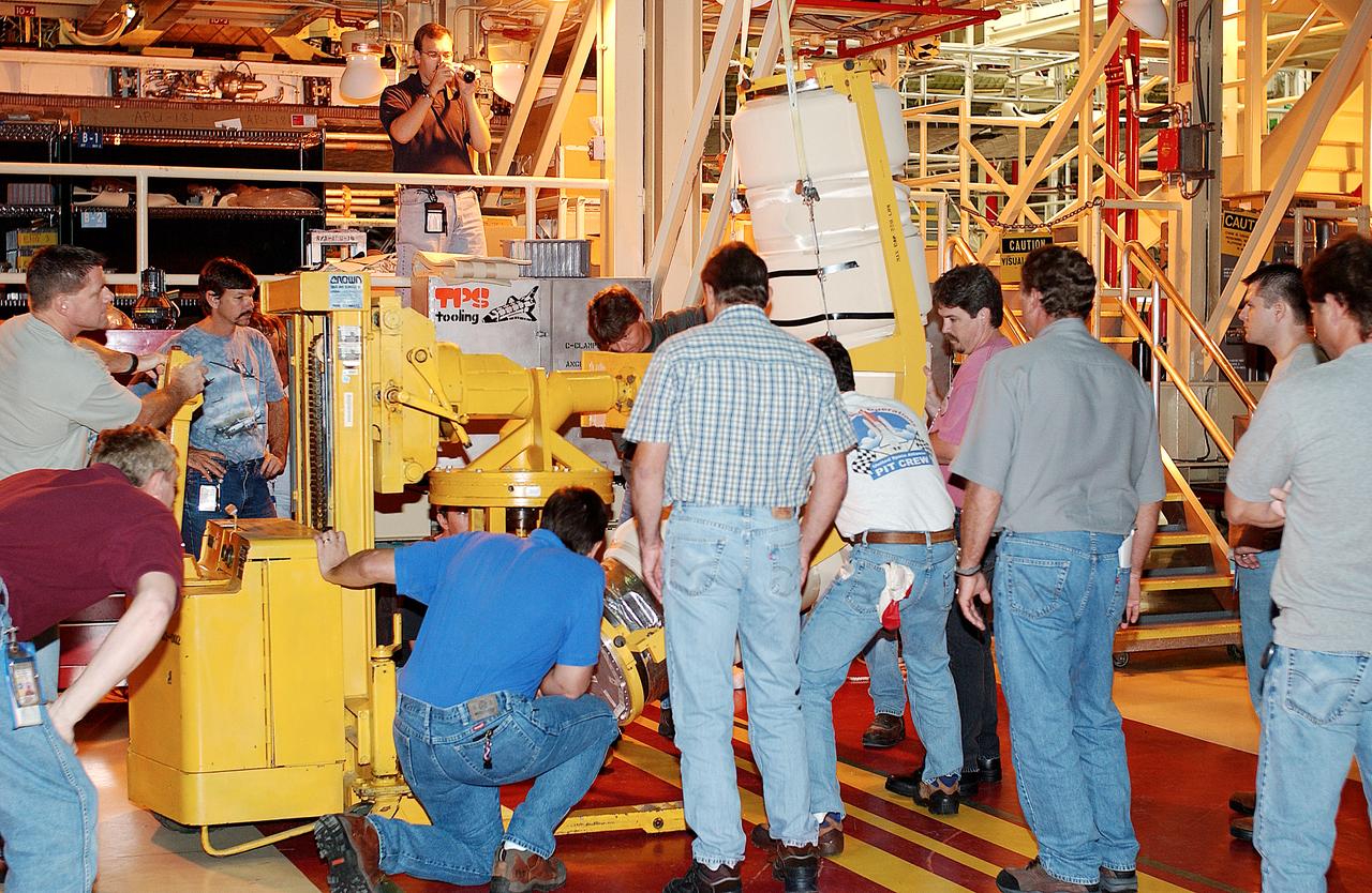 In the Orbiter Processing Facility, workers prepare to install the liquid oxygen feedline for the 17-inch disconnect on orbiter Discovery. The 17-inch liquid oxygen and liquid hydrogen disconnects provide the propellant feed interface from the external tank to the orbiter main propulsion system and the three Shuttle main engines.