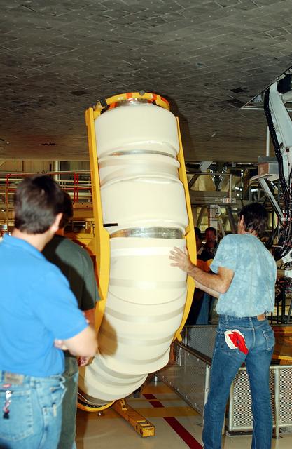 NASA image: KENNEDY SPACE CENTER, FLA. -  In the Orbiter Processing Facility, workers move the liquid oxygen feedline for the 17-inch disconnect toward orbiter Discovery for installation. The 17-inch liquid oxygen and liquid hydrogen disconnects provide the propellant feed interface from the external tank to the orbiter main propulsion system and the three Shuttle main engines.