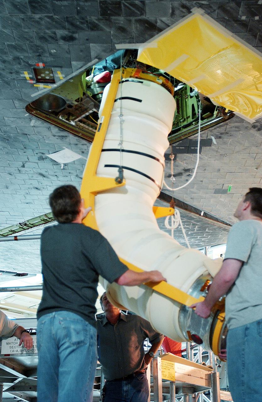 KENNEDY SPACE CENTER, FLA. -  In the Orbiter Processing Facility, workers install the liquid oxygen feedline for the 17-inch disconnect on orbiter Discovery. The 17-inch liquid oxygen and liquid hydrogen disconnects provide the propellant feed interface from the external tank to the orbiter main propulsion system and the three Shuttle main engines.