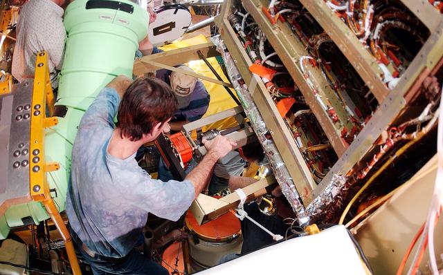 NASA image: KENNEDY SPACE CENTER, FLA. -  Viewed from inside the aft section of the orbiter Discovery, a worker installs the liquid oxygen feedline for the 17-inch disconnect, coming up from below. The 17-inch liquid oxygen and liquid hydrogen disconnects provide the propellant feed interface from the external tank to the orbiter main propulsion system and the three Shuttle main engines.