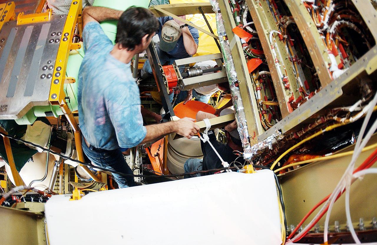 KENNEDY SPACE CENTER, FLA. -  Viewed from inside the aft section of the orbiter Discovery, a worker installs the liquid oxygen feedline for the 17-inch disconnect, coming up from below. The 17-inch liquid oxygen and liquid hydrogen disconnects provide the propellant feed interface from the external tank to the orbiter main propulsion system and the three Shuttle main engines.