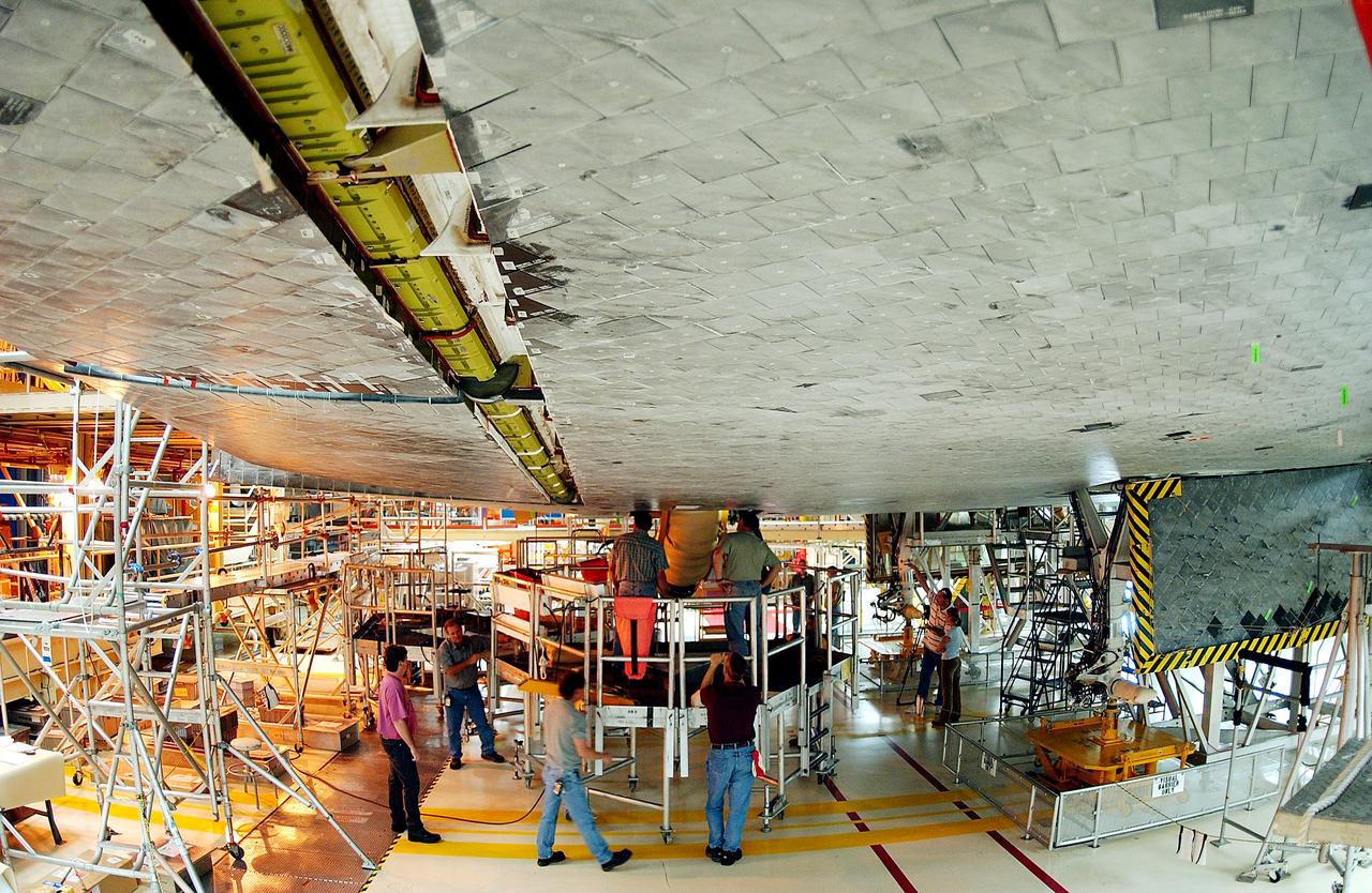 KENNEDY SPACE CENTER, FLA. -  Workers in the Orbiter Processing Facility oversee installation of the liquid oxygen feedline for the 17-inch disconnect on the orbiter Discovery.  The 17-inch liquid oxygen and liquid hydrogen disconnects provide the propellant feed interface from the external tank to the orbiter main propulsion system and the three Shuttle main engines.