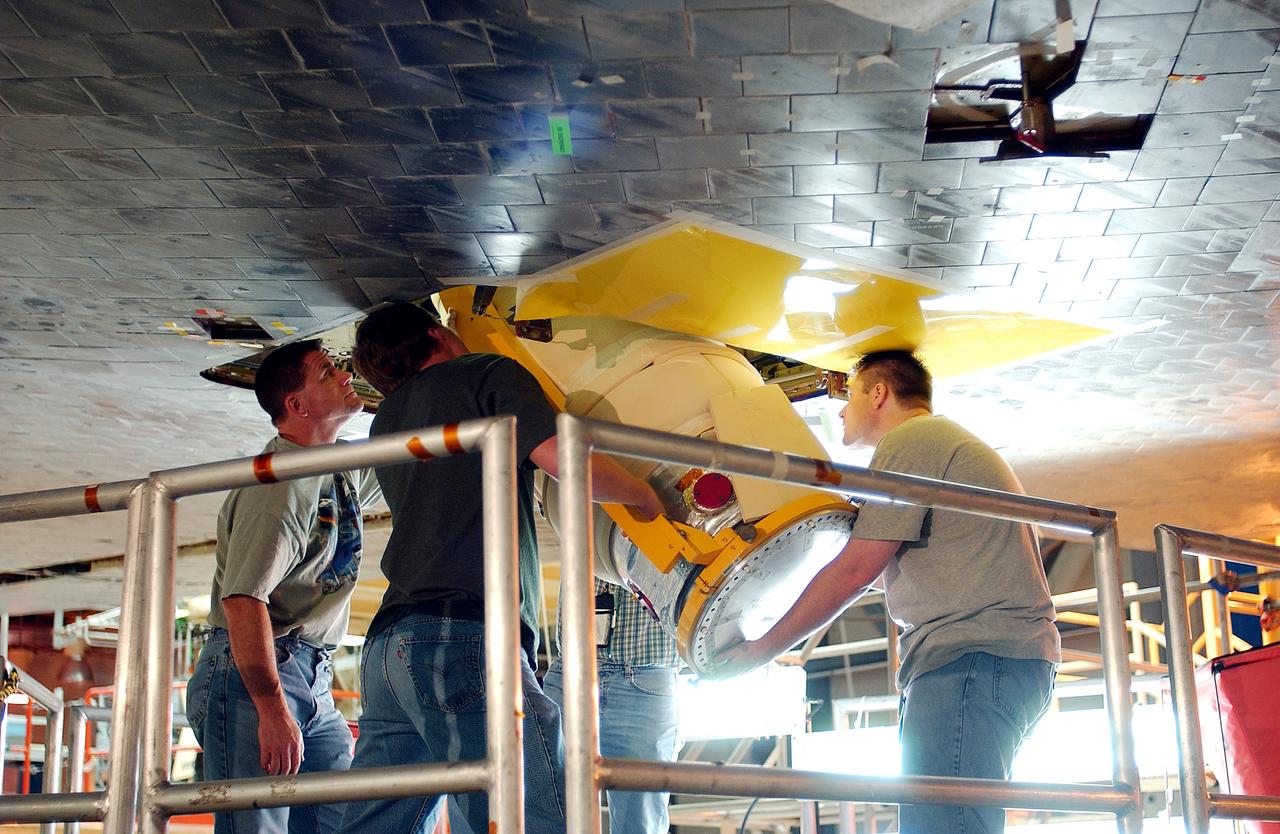 KENNEDY SPACE CENTER, FLA. -  Workers in the Orbiter Processing Facility insert the liquid oxygen feedline for the 17-inch disconnect in the orbiter Discovery.  The 17-inch liquid oxygen and liquid hydrogen disconnects provide the propellant feed interface from the external tank to the orbiter main propulsion system and the three Shuttle main engines.