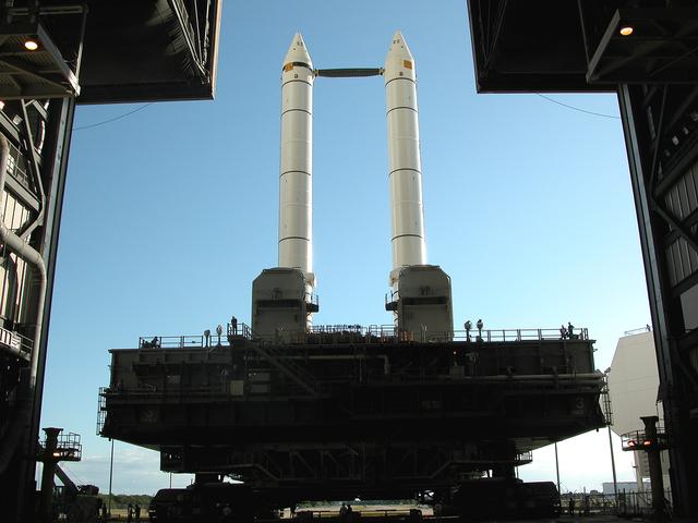 NASA image: KENNEDY SPACE CENTER, FLA. -  The crawler transporter slowly moves the Mobile Launcher Platform (MLP), carrying a set of twin solid rocket boosters, away from the Vehicle Assembly Building (VAB) in support of engineering analysis vibration tests on the crawler and MLP.   The crawler is moving at various speeds up to 1 mph in an effort to achieve vibration data gathering goals as it leaves the VAB and then returns.  The boosters are braced at the top for stability.  The primary purpose of these rollout tests is to gather data to develop future maintenance requirements on the transport equipment and the flight hardware. Various parts of the MLP and crawler transporter have been instrumented with vibration data collection equipment.