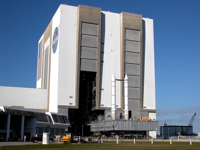 NASA image: KENNEDY SPACE CENTER, FLA. -  The crawler transporter slowly moves the Mobile Launcher Platform (MLP), carrying a set of twin solid rocket boosters, out of the Vehicle Assembly Building (VAB) in support of engineering analysis vibration tests on the crawler and MLP.   The crawler is moving at various speeds up to 1 mph in an effort to achieve vibration data gathering goals as it leaves the VAB and then returns.  The boosters are braced at the top for stability.  The primary purpose of these rollout tests is to gather data to develop future maintenance requirements on the transport equipment and the flight hardware. Various parts of the MLP and crawler transporter have been instrumented with vibration data collection equipment.