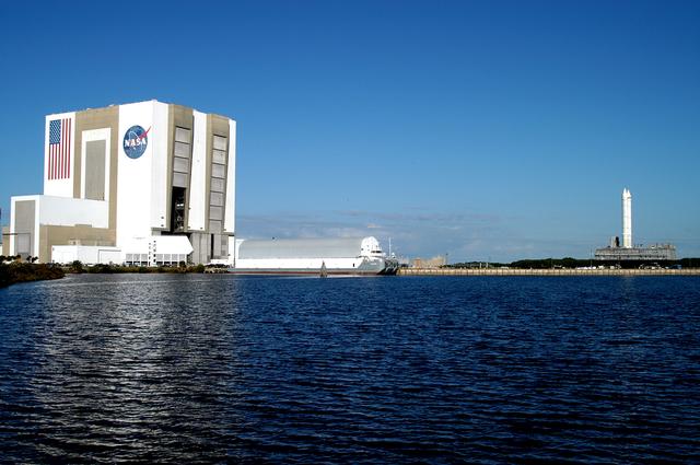 NASA image: KENNEDY SPACE CENTER, FLA. - Viewed across the turn basin in the Launch Complex 39 Area, the crawler transporter slowly moves the Mobile Launcher Platform (MLP), carrying a set of twin solid rocket boosters, away from the Vehicle Assembly Building (VAB).  The journey is in support of engineering analysis vibration tests on the crawler and MLP.  The water on the right of the crawlerway is the Banana River.  The crawler is moving at various speeds up to 1 mph in an effort to achieve vibration data gathering goals as it leaves the VAB and then returns.  The boosters are braced at the top for stability.  The primary purpose of these rollout tests is to gather data to develop future maintenance requirements on the transport equipment and the flight hardware. Various parts of the MLP and crawler transporter have been instrumented with vibration data collection equipment.