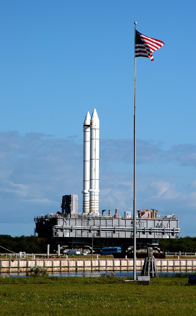 KENNEDY SPACE CENTER, FLA. - Carrying a set of twin solid rocket boosters, the crawler transporter slowly moves the Mobile Launcher Platform (MLP) past the NASA-KSC News Center where the U.S. flag flies daily.  The journey is in support of engineering analysis vibration tests on the crawler and MLP. The crawler is moving at various speeds up to 1 mph in an effort to achieve vibration data gathering goals as it leaves the VAB and then returns.  The boosters are braced at the top for stability.  The primary purpose of these rollout tests is to gather data to develop future maintenance requirements on the transport equipment and the flight hardware. Various parts of the MLP and crawler transporter have been instrumented with vibration data collection equipment.